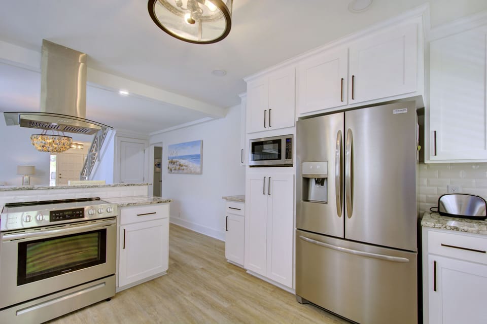 Kitchen View Toward Dining Area - Stainless appliances, white cabinetry, and the nearby dining table keep the main floor practical for cooking and serving.
