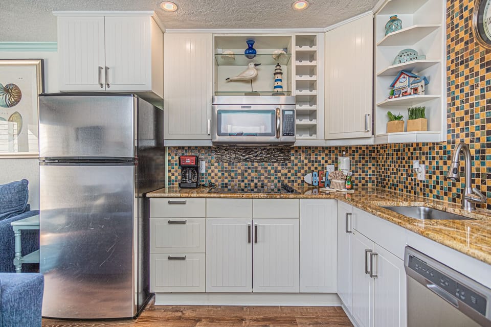 Kitchen is equipped with a fridge/freezer, stove top, microwave, and a dishwasher