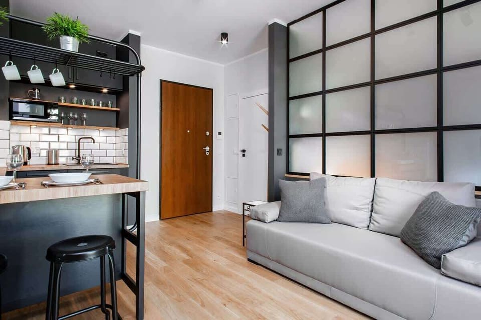 This living room has a spacious feel with a large gray sofa. The windows allow a lot of natural light to fill the room.