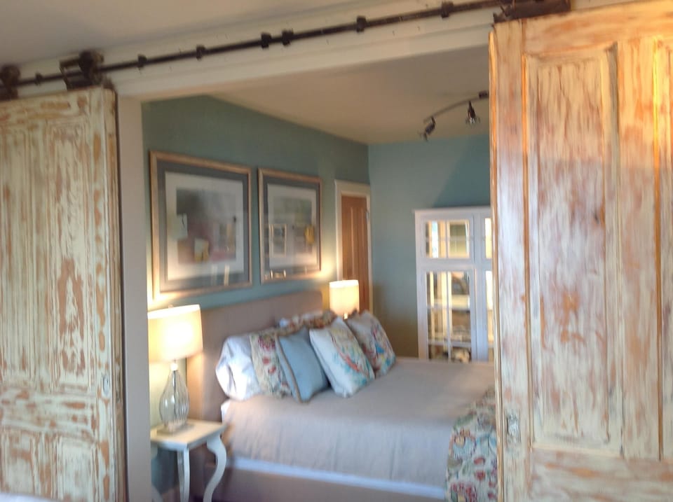 Antique doors draw you into the peaceful main floor bedroom with a bath and view