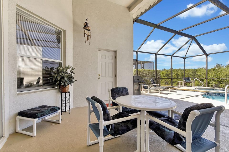Covered patio with ceiling fan, table and lounge chairs.