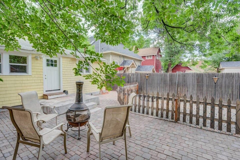Sun-dappled patio with outdoor dining set and a cast-iron chiminea—sip coffee, share stories by the fire, and linger under the trees with the fenced yard adding a cozy sense of privacy.