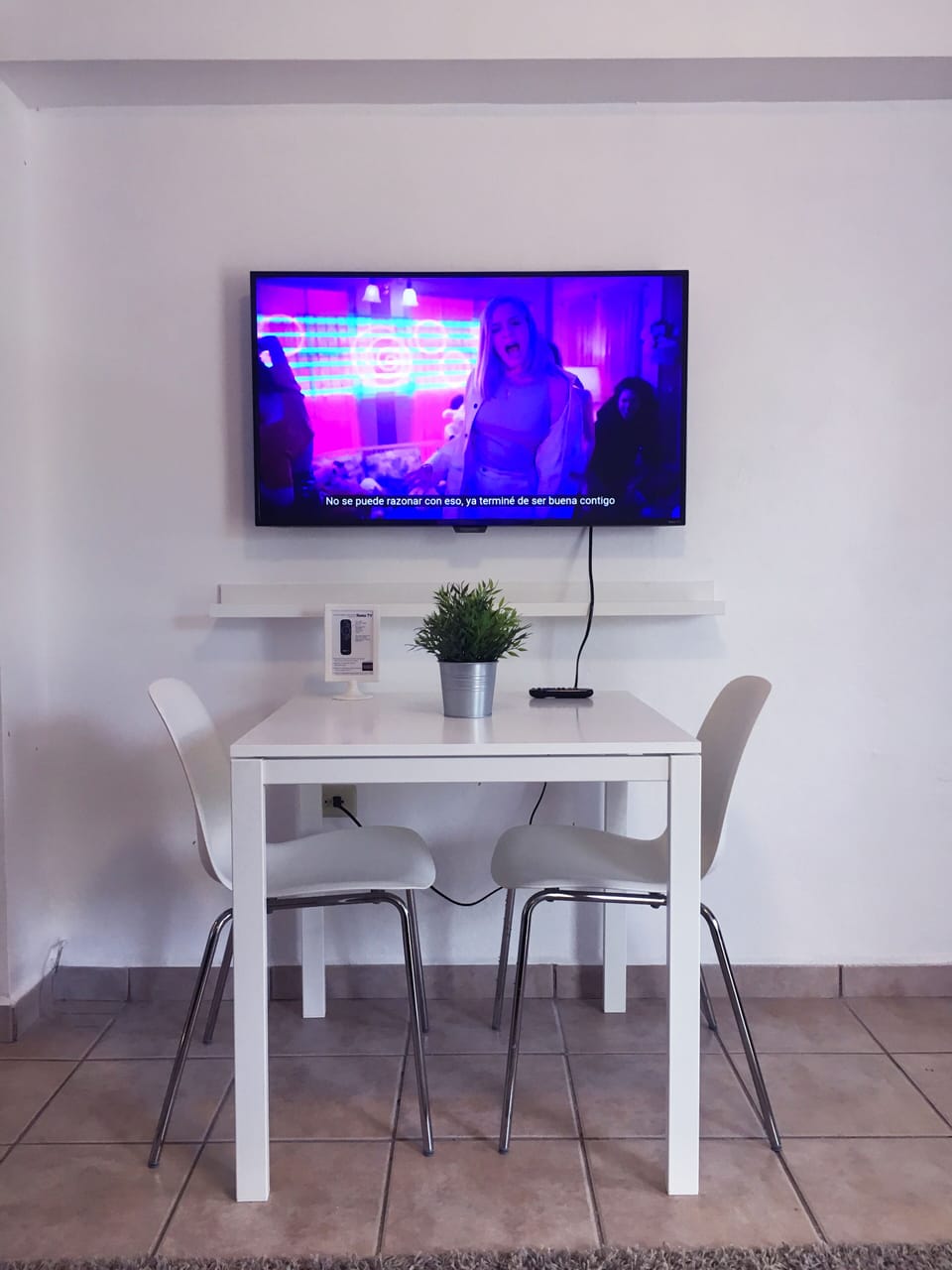 Area de comedor con 2 sillas, smart TV y esta proximo al area de cocina.