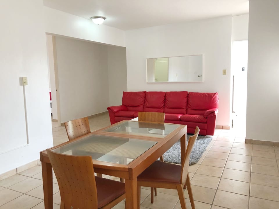Area de comedor con 4 sillas, smart TV y esta proximo al area de cocina.