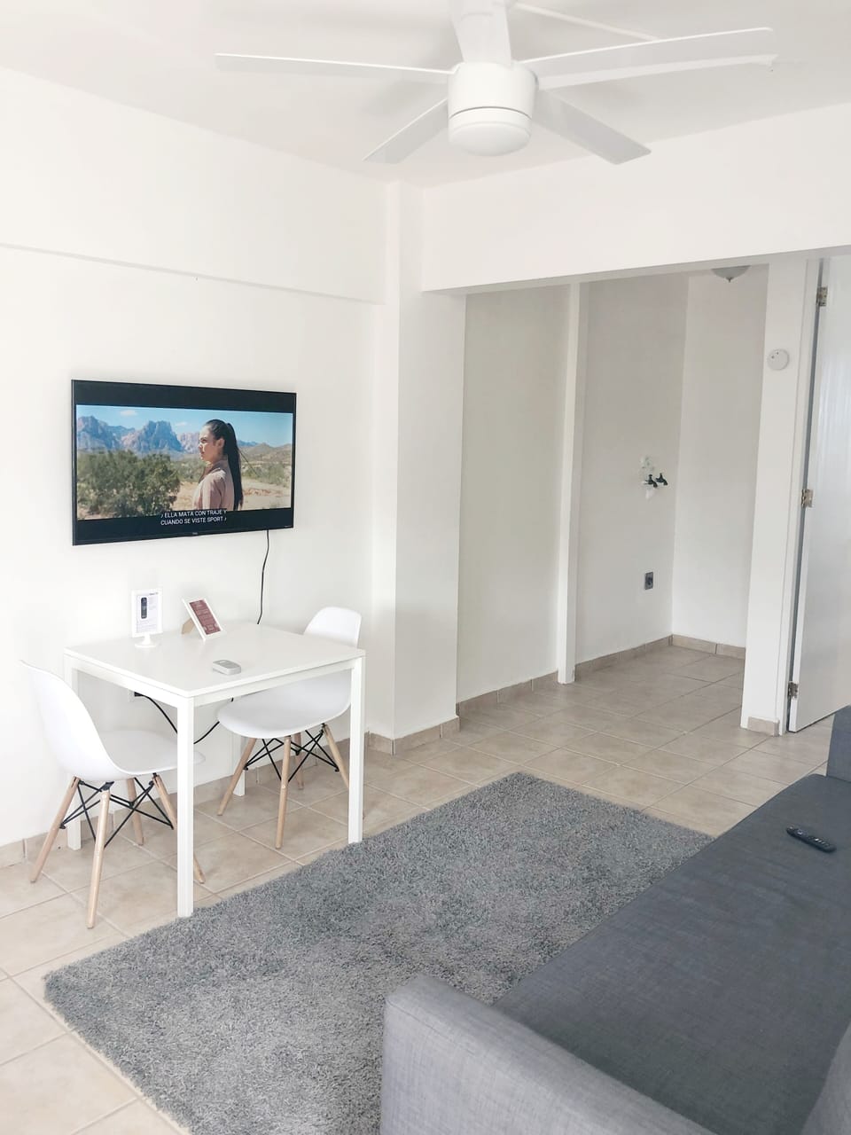 Area de comedor con 2 sillas, smart TV y esta proximo al area de cocina.