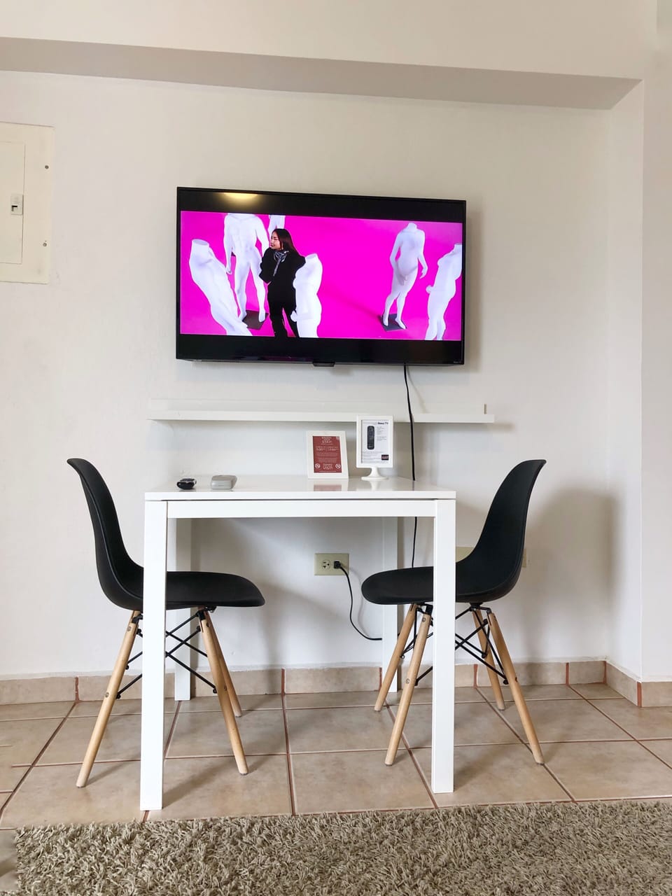 Area de comedor con 2 sillas, smart TV y esta proximo al area de cocina.