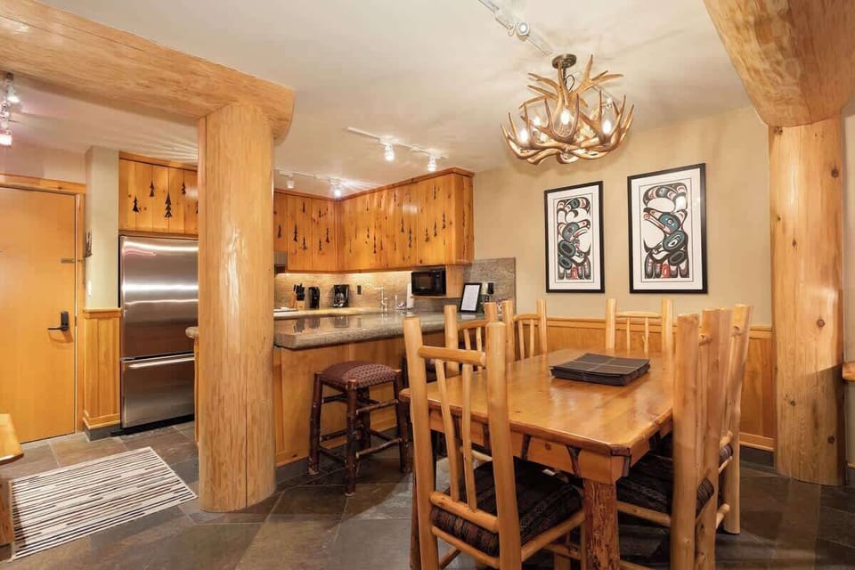 - Dine beneath an antler chandelier in this rustic alpine setting  
- Handcrafted wood furniture adds mountain charm and warmth  
- Open space connects to kitchen for cozy shared meals  
