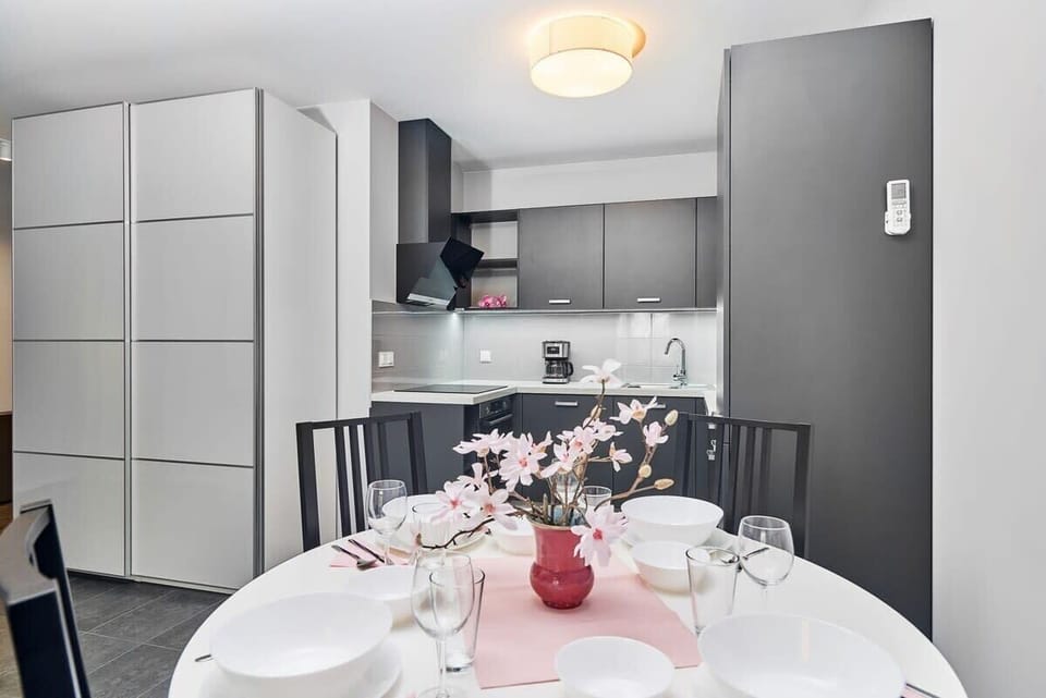 Kitchen of Świstackiego 19/10 with dining area, stove, oven, fridge, dishwasher, kettle, coffee machine, toaster and cupboards
