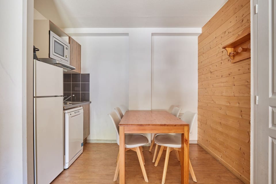 Dining table with white chairs beside the kitchenette