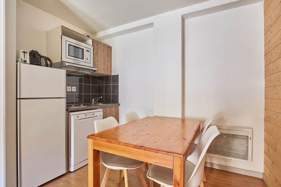 Kitchen area with a white fridge, microwave and dining table