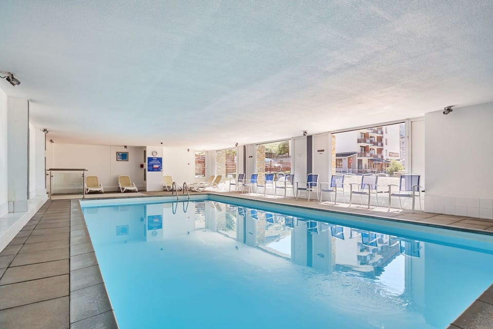 Indoor pool with large windows and a wall clock
