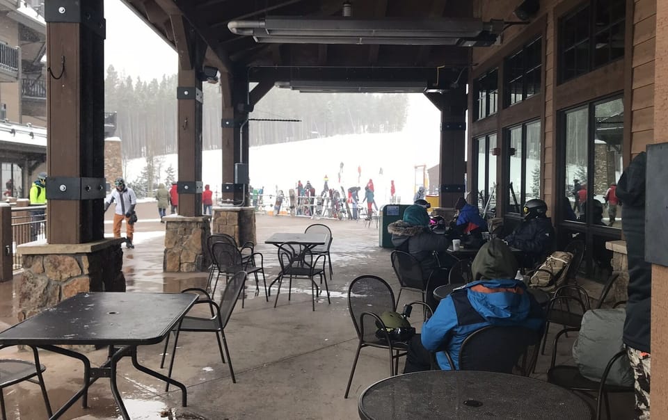 Seating by the side of the building at the bottom of the slope on a snowy day
