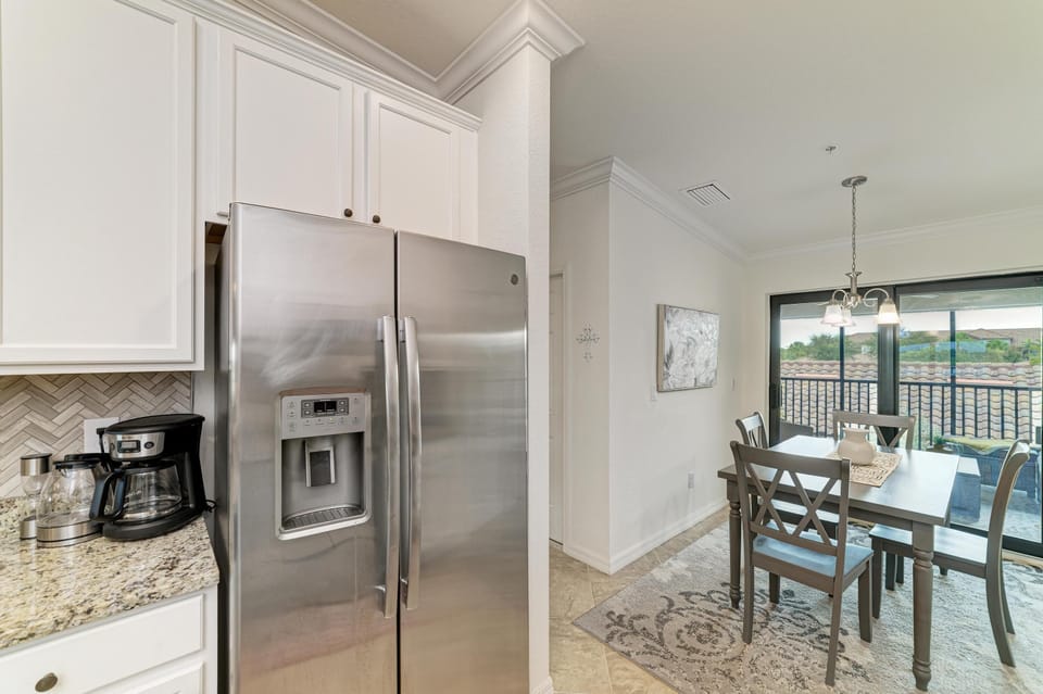 Dining area with gray wooden table and chairs on patterned rug, sliding glass doors open to balcony.