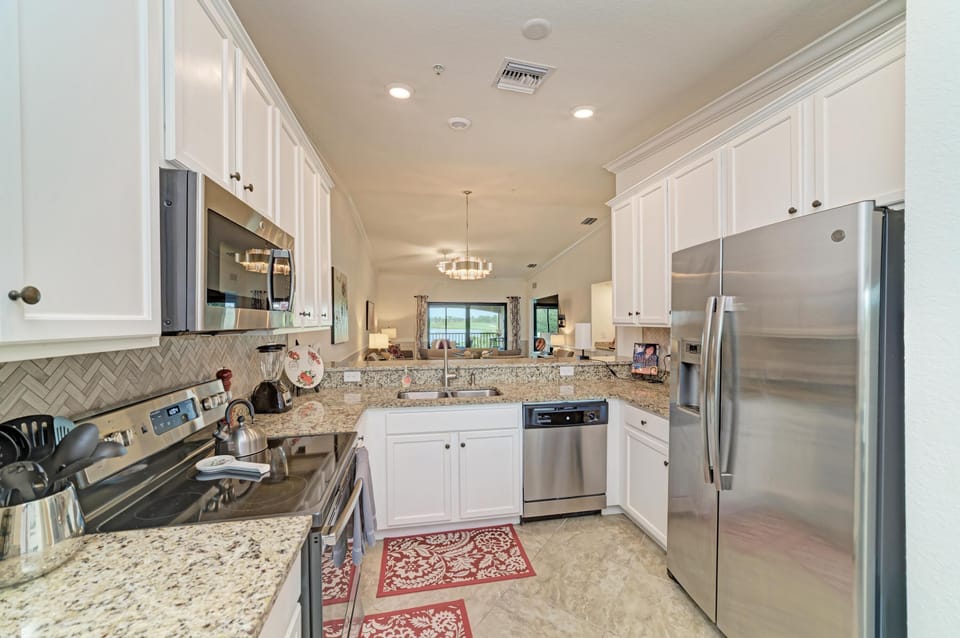Stainless steel appliances line the kitchen with granite counters, white cabinets, and beige tile flooring.