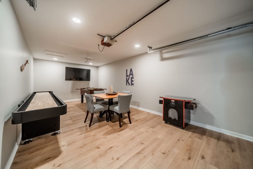 Garage converted game room with shuffleboard, arcade game, foosball & card table.