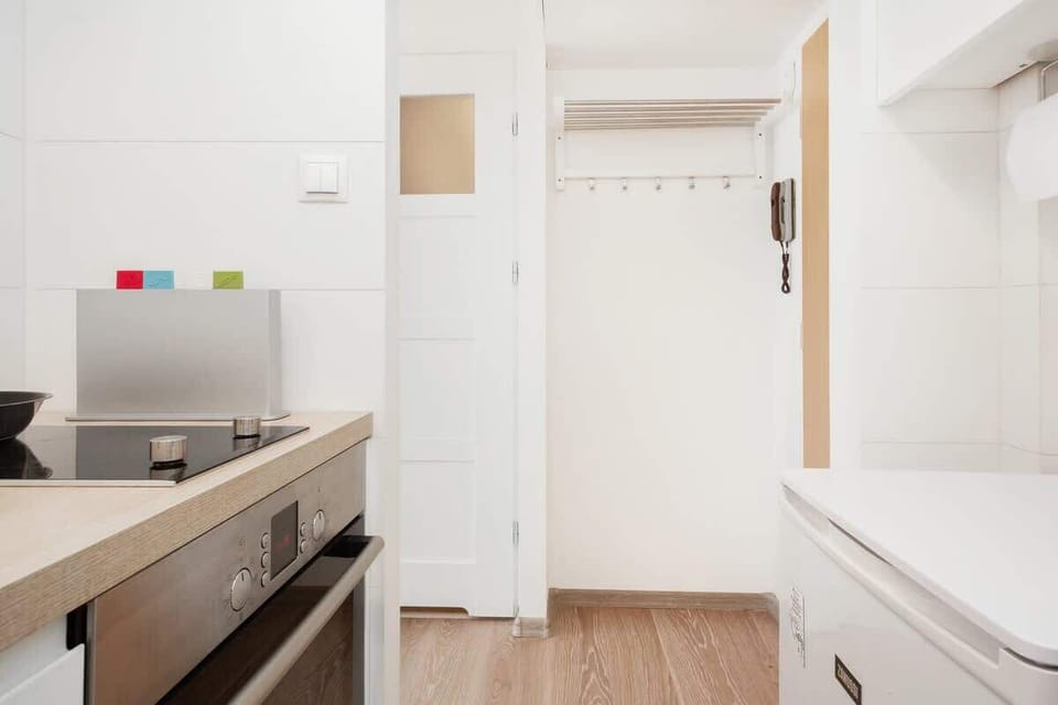 Another angle of the kitchen showing countertop space, storage, and minimalist white cabinetry.