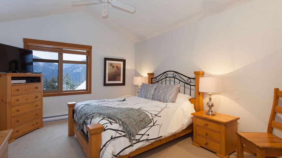 - Bedroom with king bed and natural wood furnishings throughout  
- Large window frames stunning mountain views at sunrise  
- Peaceful alpine-inspired space for restful nights  
