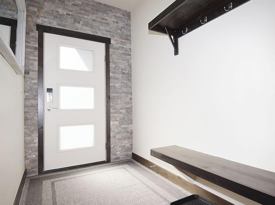 Store your belongings on the sleek built-in bench while hanging coats on convenient wall hooks in this modern entryway.