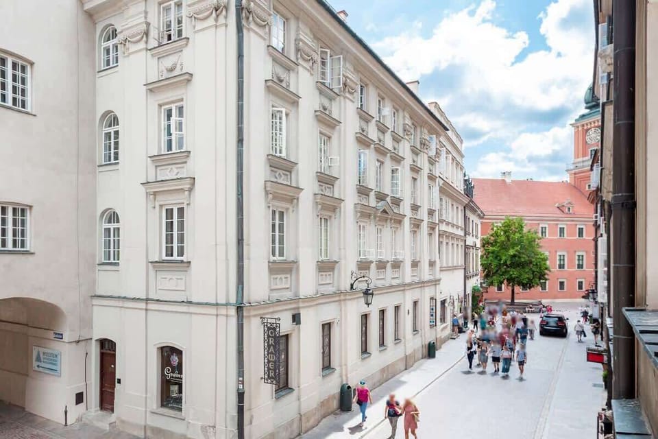 A scenic view of a historic street with colorful buildings and cobblestone paths. People are walking and enjoying the atmosphere.
