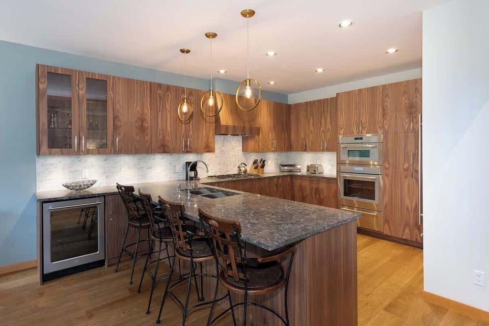 - Gourmet kitchen with marble counters and pendant lights over island seating  
- Fully stocked and ready for shared meals or casual morning breakfasts  
- Modern design with wood finishes that complement the mountain style  