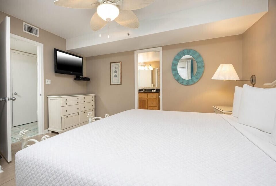 Bedroom featuring a large king bed, a mounted TV, and an en-suite bathroom with stylish decor