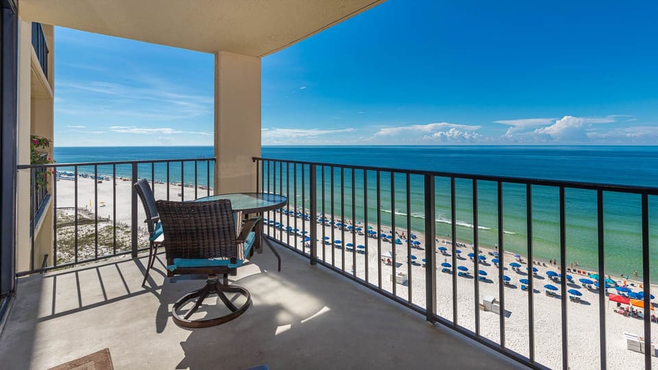 Enjoy breathtaking views from the balcony, featuring a table and chairs overlooking the serene beach and vibrant umbrellas