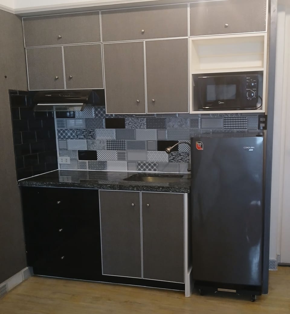 The kitchen has a refrigerator, microwave,  rice cooker and kettle.