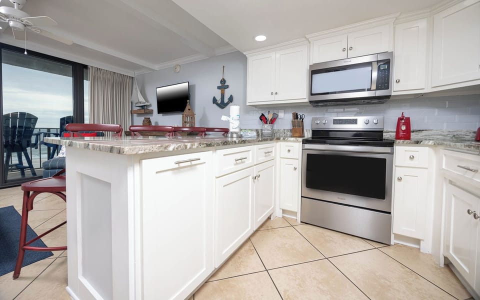 The modern kitchen features sleek stainless appliances and a view of the beachfront from the adjacent seating area