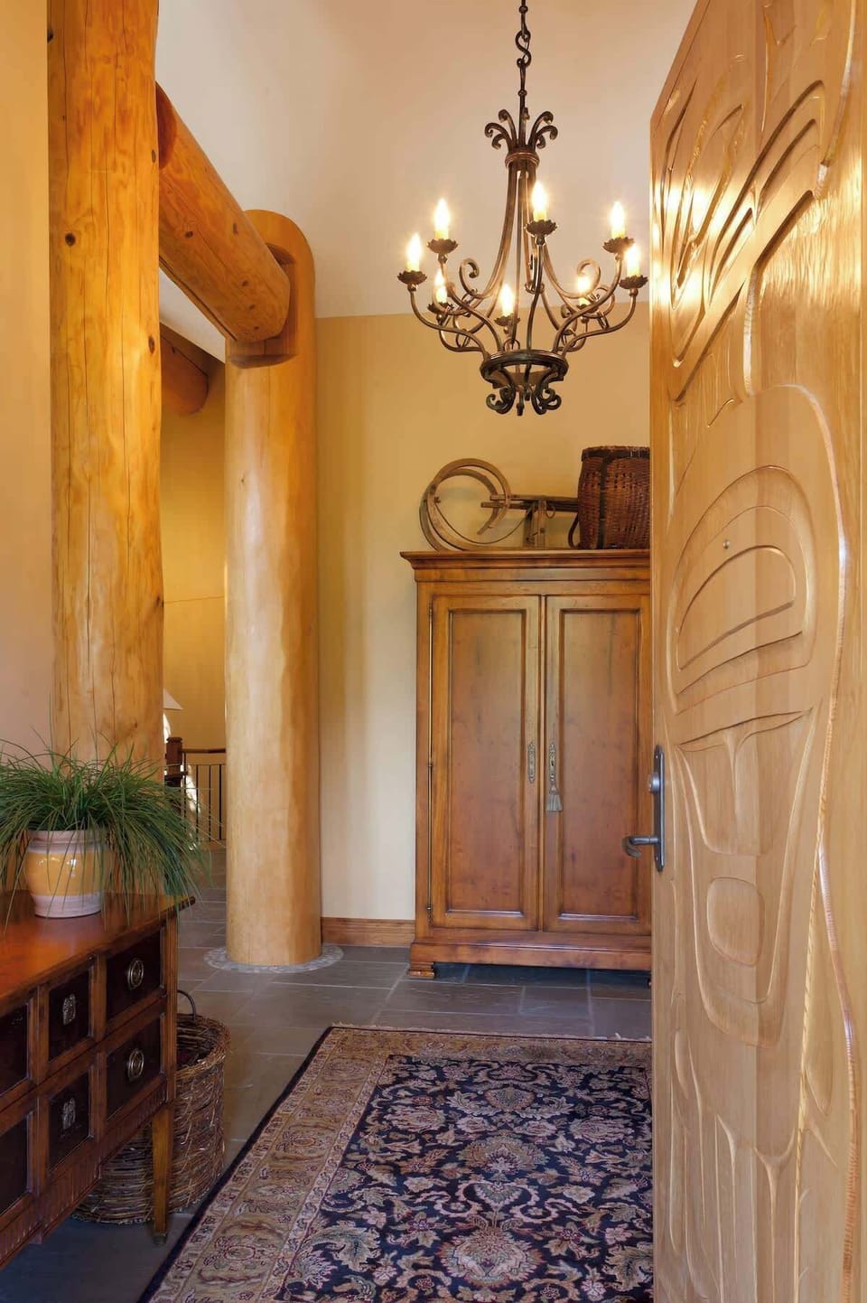 - Elegant entryway with carved wood door, chandelier lighting, and mountain décor  
- Warm tones and natural textures create a welcoming alpine first impression  
- Step inside to a space blending rustic charm and Whistler lodge sophistication  
