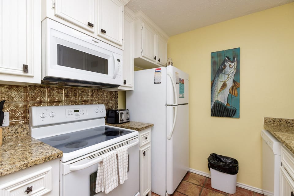 Cook your favorite meals in this bright kitchen with granite counters, white appliances, and decorative tile backsplash.