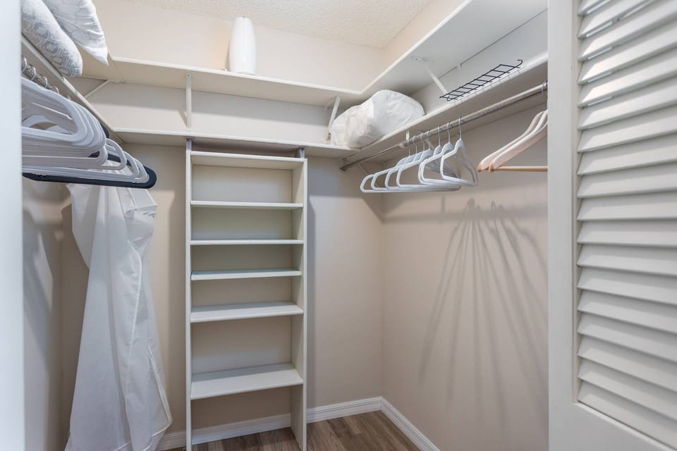 Master bedroom walk-in closet with ample shelf space and hangars.