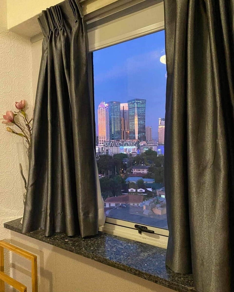 The corner window overlooks the Rizal mountains and Ortigas skyline.