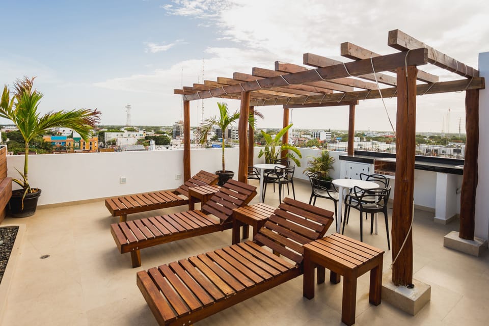 Tables and chairs next to the swimming pool to relax and a cooking grill