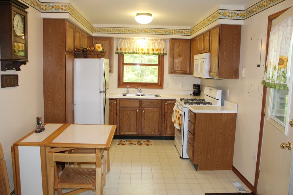 Kitchen with plates, coffee mugs, coffee maker, toaster, ice trays & glassware.
