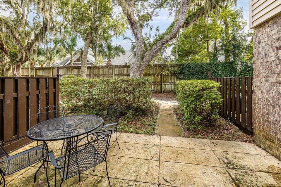 Fenced patio with bistro table and trees
