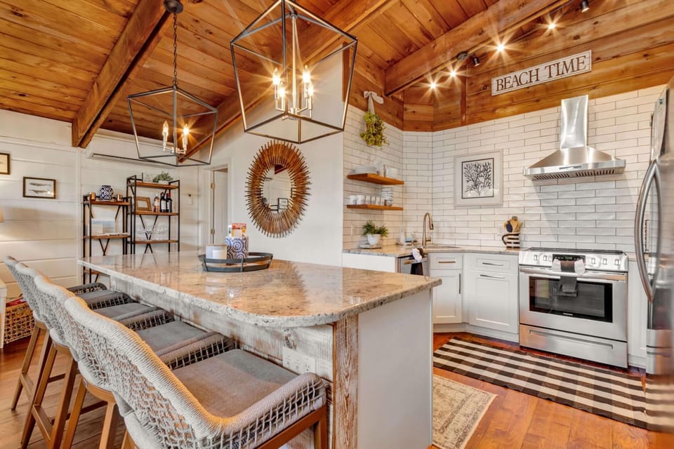 Bright coastal kitchen with modern appliances, granite counters, and a spacious island with seating.