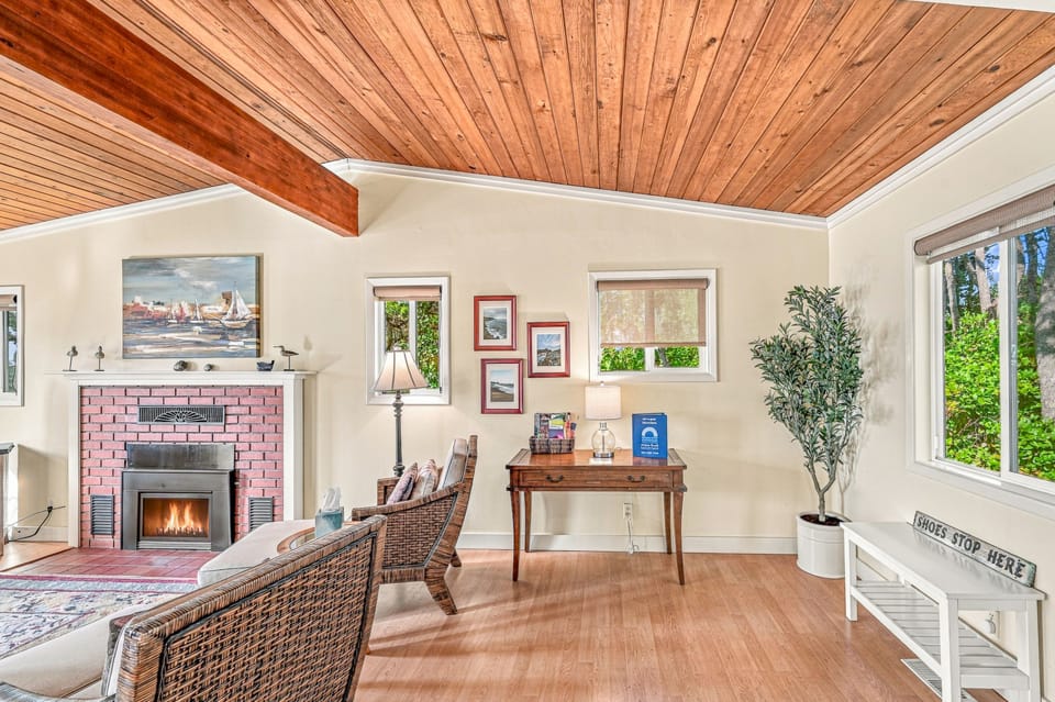 Relax under stunning wood-beamed ceilings in your bright, inviting living space. The cozy fireplace and natural light create a warm retreat for your stay.