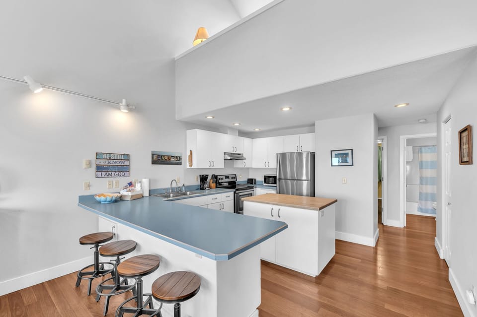 Your spacious kitchen invites culinary adventures with gleaming appliances, generous counter space, and breakfast bar seating for casual meals together.