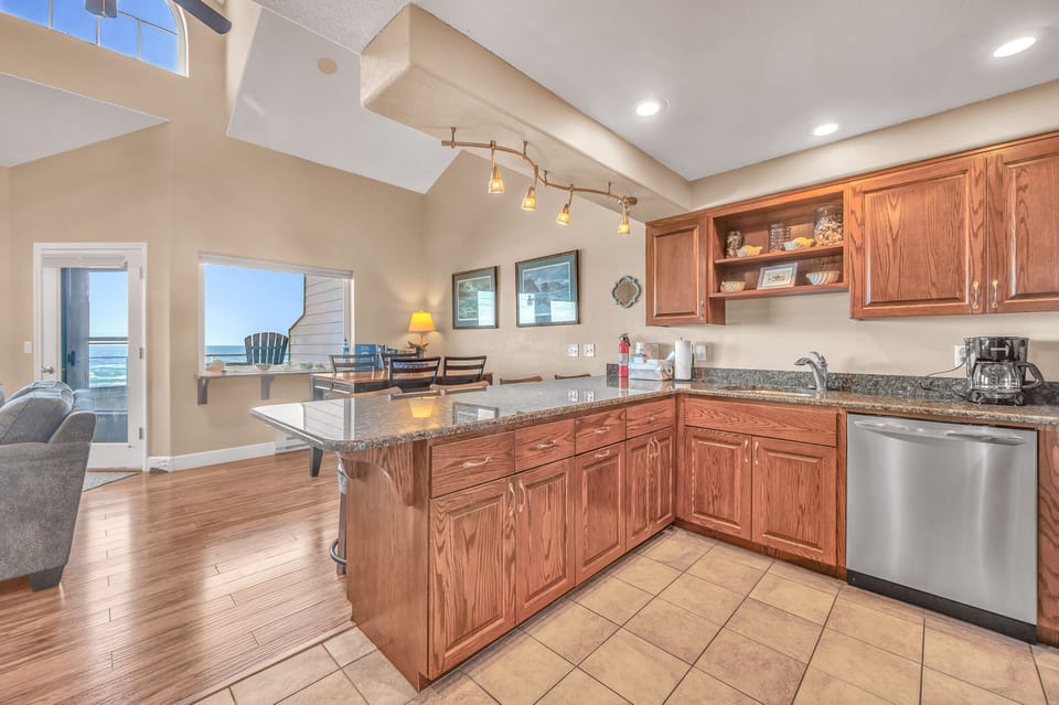 Your fully equipped kitchen flows into the bright living space, perfect for preparing meals while enjoying ocean glimpses through the windows.