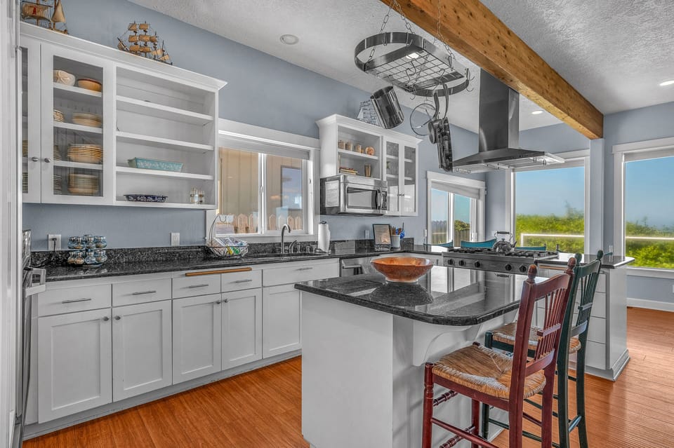 Your chef's kitchen features granite countertops, white cabinetry, and a cozy island where morning coffee tastes even better with scenic views.
