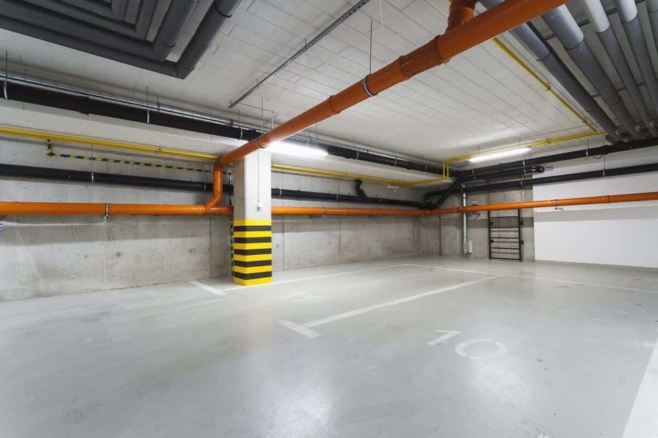 Another view of an empty underground parking lot, showing clean, spacious areas for vehicles. The lighting is bright and efficient.