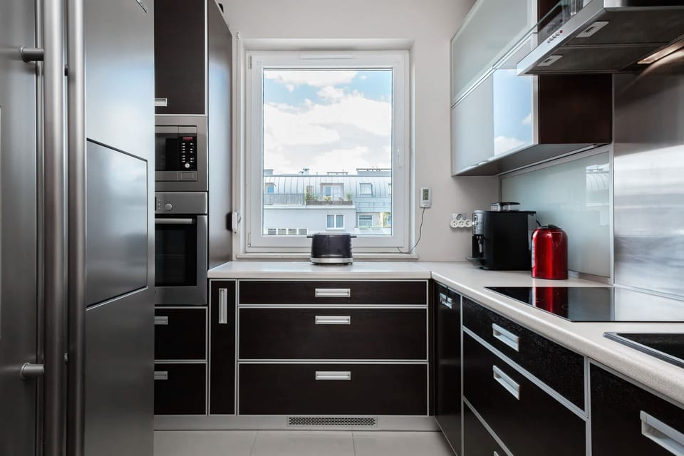 A contemporary kitchen with high-gloss black cabinetry, stainless steel appliances, and a sleek countertop, offering a streamlined, modern look.