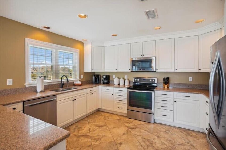 Gather around this spacious, sunlit kitchen where you can whip up meals with modern appliances and granite countertops. Large windows invite natural light, making every culinary moment feel bright and welcoming.