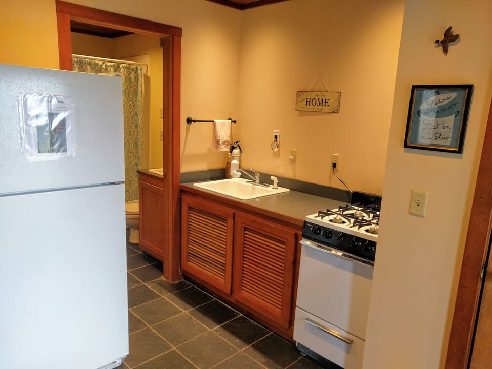 Kitchen with full size refrigerator, supply closet, sink, stove and oven.