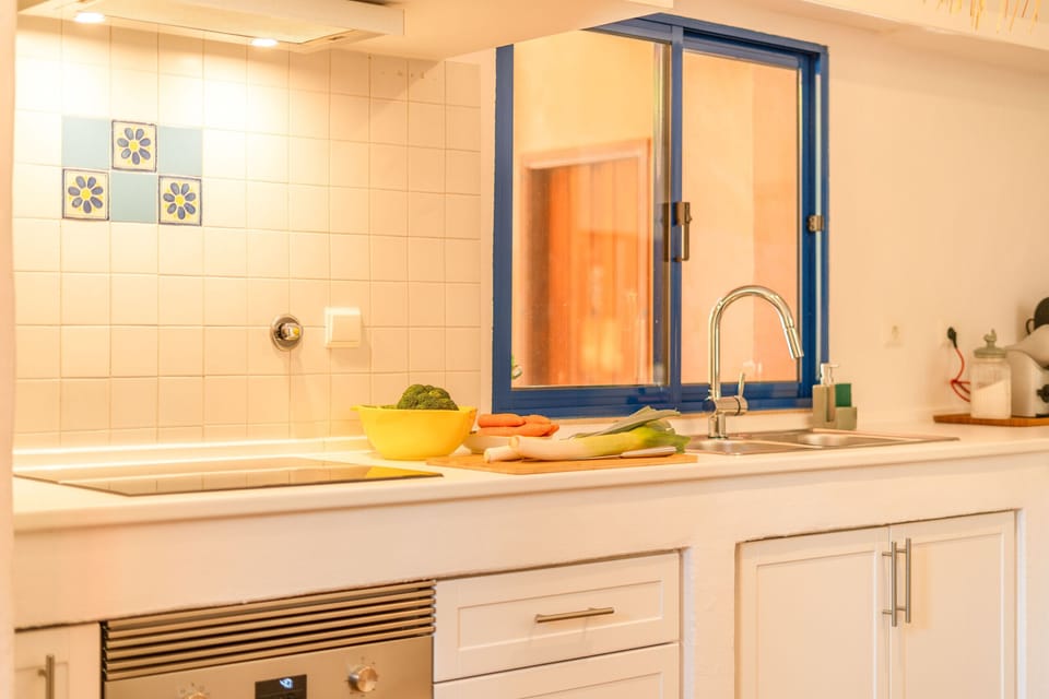 Bright kitchen with blue-framed window and yellow bowl — Villa Bambu, holiday villa in Herdade de Aroeira