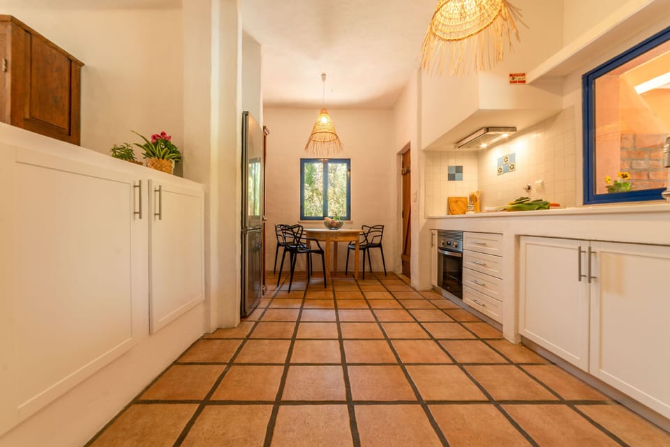Modern kitchen with terracotta tile flooring and dining area — Villa Bambu, luxury holiday villa in Herdade de Aroeira