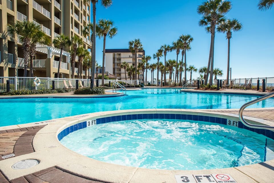 Dive into crystal-clear waters while palm trees sway overhead. The sparkling pool and bubbling hot tub create your perfect beach getaway oasis.