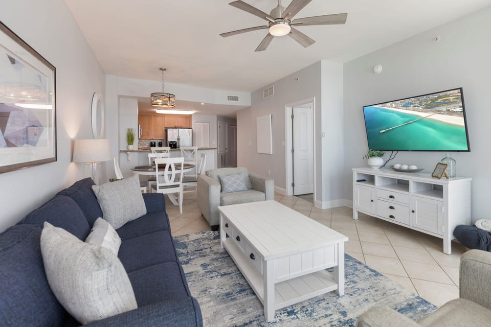 Unwind in your bright, coastal-themed living space with plush seating, modern entertainment, and a seamless flow to the kitchen.