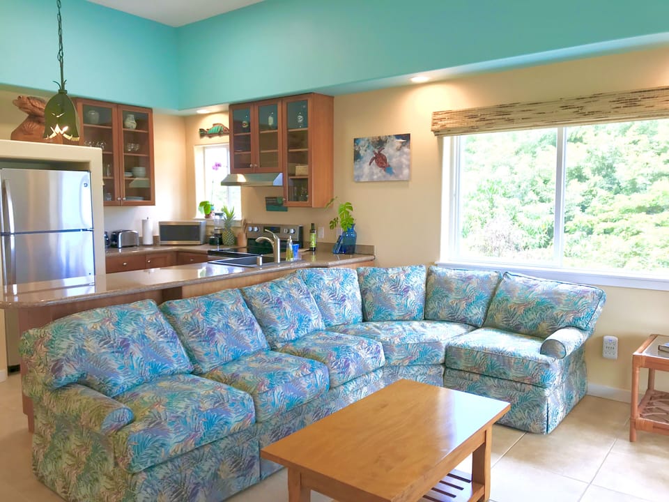 Open concept great room with high ceilings and treetop and ocean views.