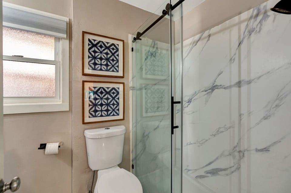 Full bath featuring marble-style shower & glass enclosure.